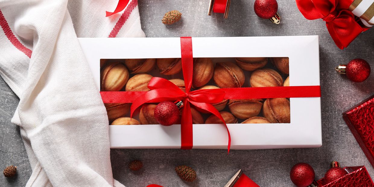 A box of gourmet nuts wrapped in a box with a red bow.