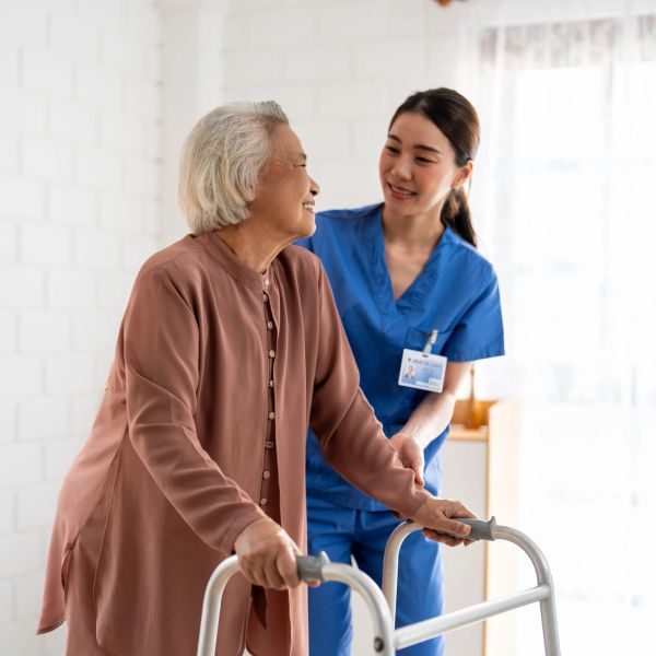 Caregiver assisting elderly woman with walker.