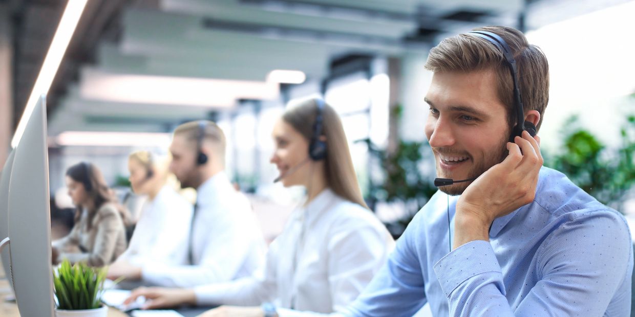 Call center employees working with headsets in a bright office.