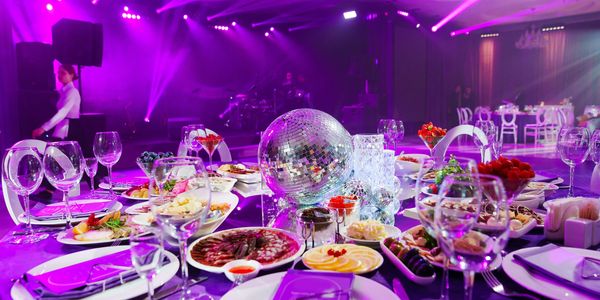 Elegant banquet table with a disco ball centerpiece and purple lighting.