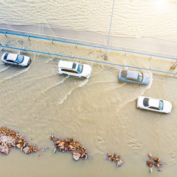 Aerial view of cars driving through a flooded road with murky water.