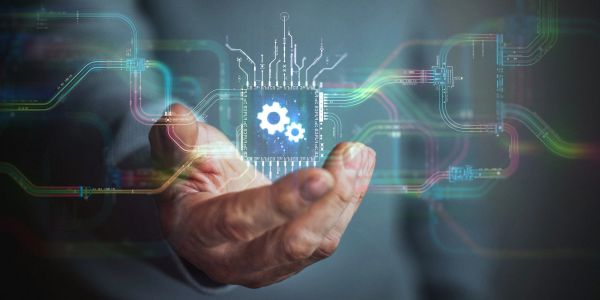 Hand holding a digital microchip with gears, symbolizing technology and innovation.