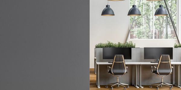 Modern office space with black chairs, pendant lights, and large windows overlooking trees.