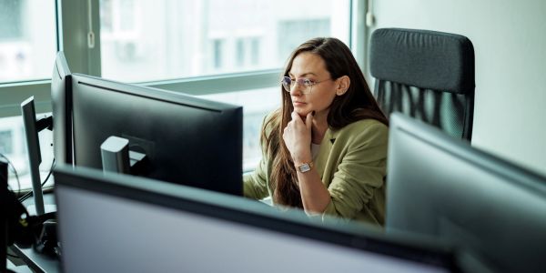 A woman focused on her computer screen in an office setting.