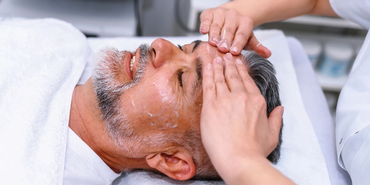 Man receiving a facial massage at a spa.