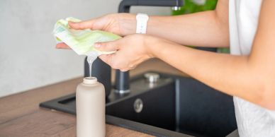 Person refilling a reusable bottle with water over a kitchen sink.