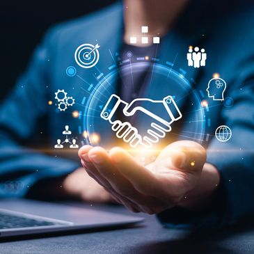 Businessman holding glowing handshake icon surrounded by business-related symbols.