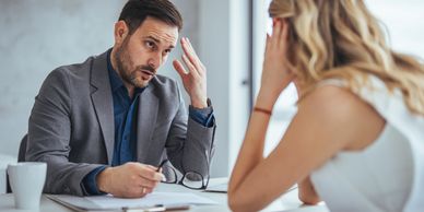 A man discussing seriously with a woman at an office desk.