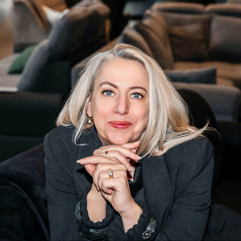 Confident Silver-Haired Woman Smiling with Hands Clasped in Furniture Store