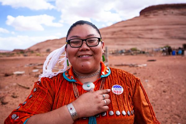 Smiling person wearing traditional clothing and an "I Voted" sticker.