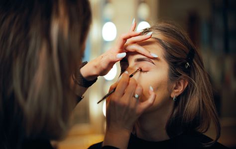 A makeup artist applying eyeshadow on a woman.