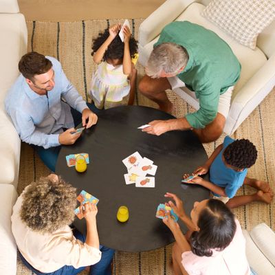 A multi-generational family playing cards around a round table.