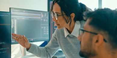 Two people discussing code on a computer screen.