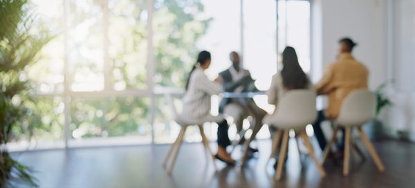 Blurry image of people having a meeting in a bright room.