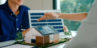 People discussing solar panels for a model house indoors.