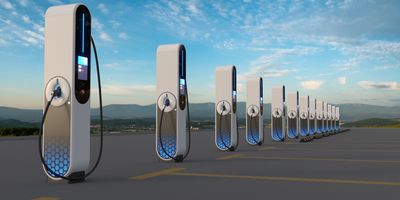 Row of modern electric vehicle charging stations under a clear sky.