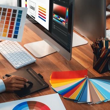 Designers working on color palettes and logo design at a shared workspace.