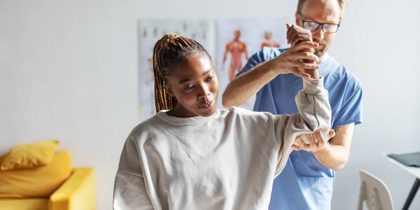 Therapist helping patient with arm rehabilitation exercises.