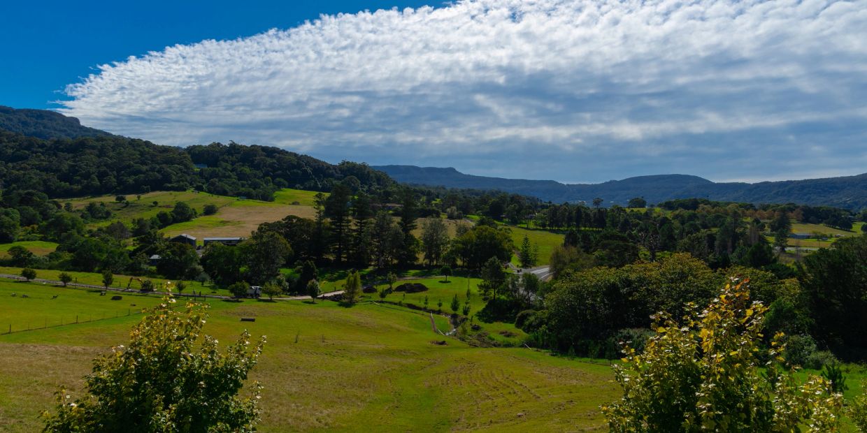 Scenic countryside with rolling green hills and cloudy sky.