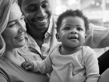 Happy parents holding their joyful baby at home.
