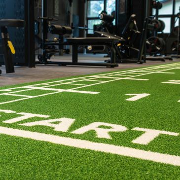 Indoor gym with artificial turf marked with a START line for workouts.