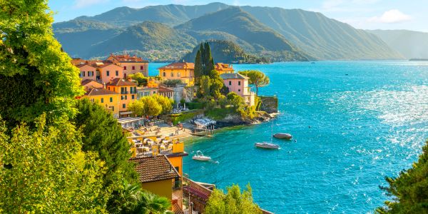 Colorful lakeside village nestled by clear blue water and green mountains, lake como italy, italy tour packages, naple venice sightseeing, europe tour packages