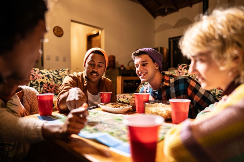 LGBTQIA+ friends playing board games on living room at home