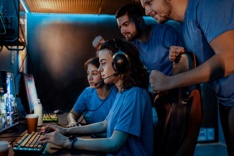 Cybersport Gamers Expressing Success While Raising Hands Up and Smiling During Participation in Esports Tournament in Computer Club