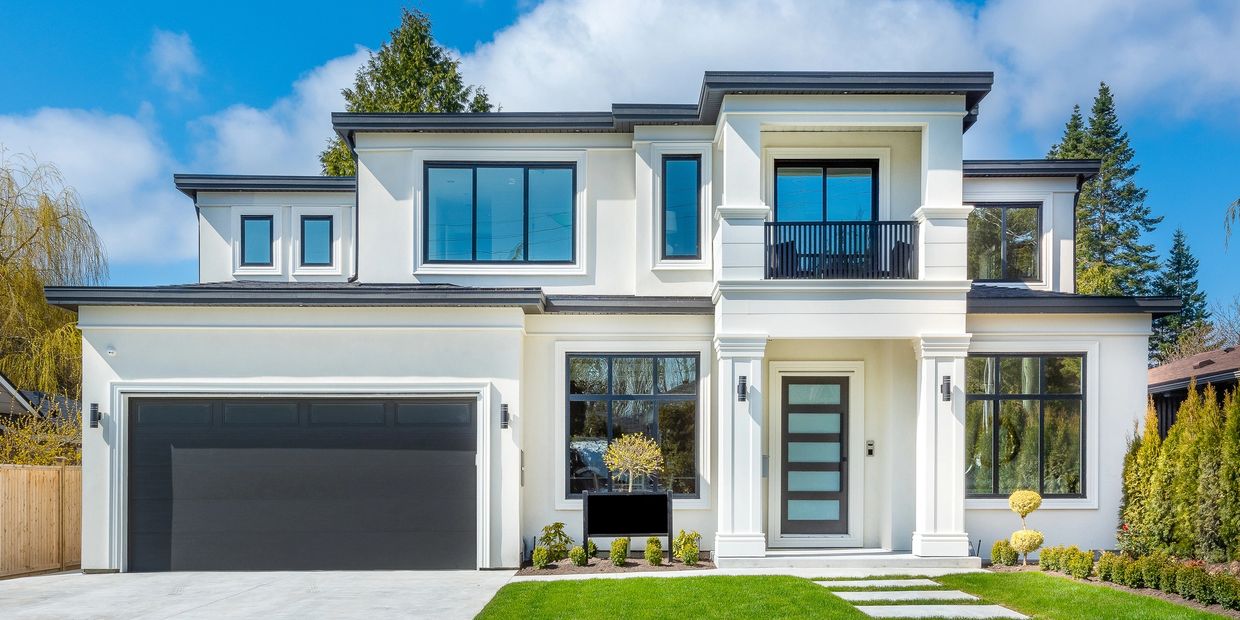 Modern two-story white house with black accents and a well-kept lawn.
