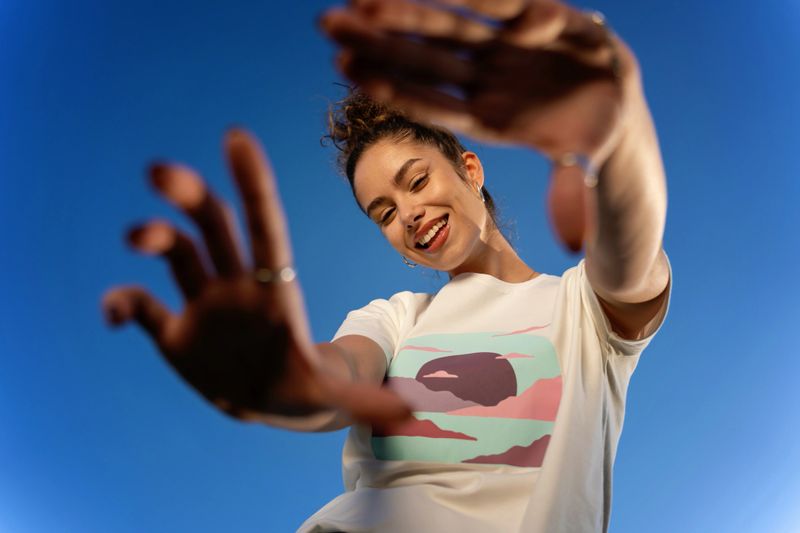 Young woman posing outdoors against a clear blue sky, her fashionable attire shining under the natural light.