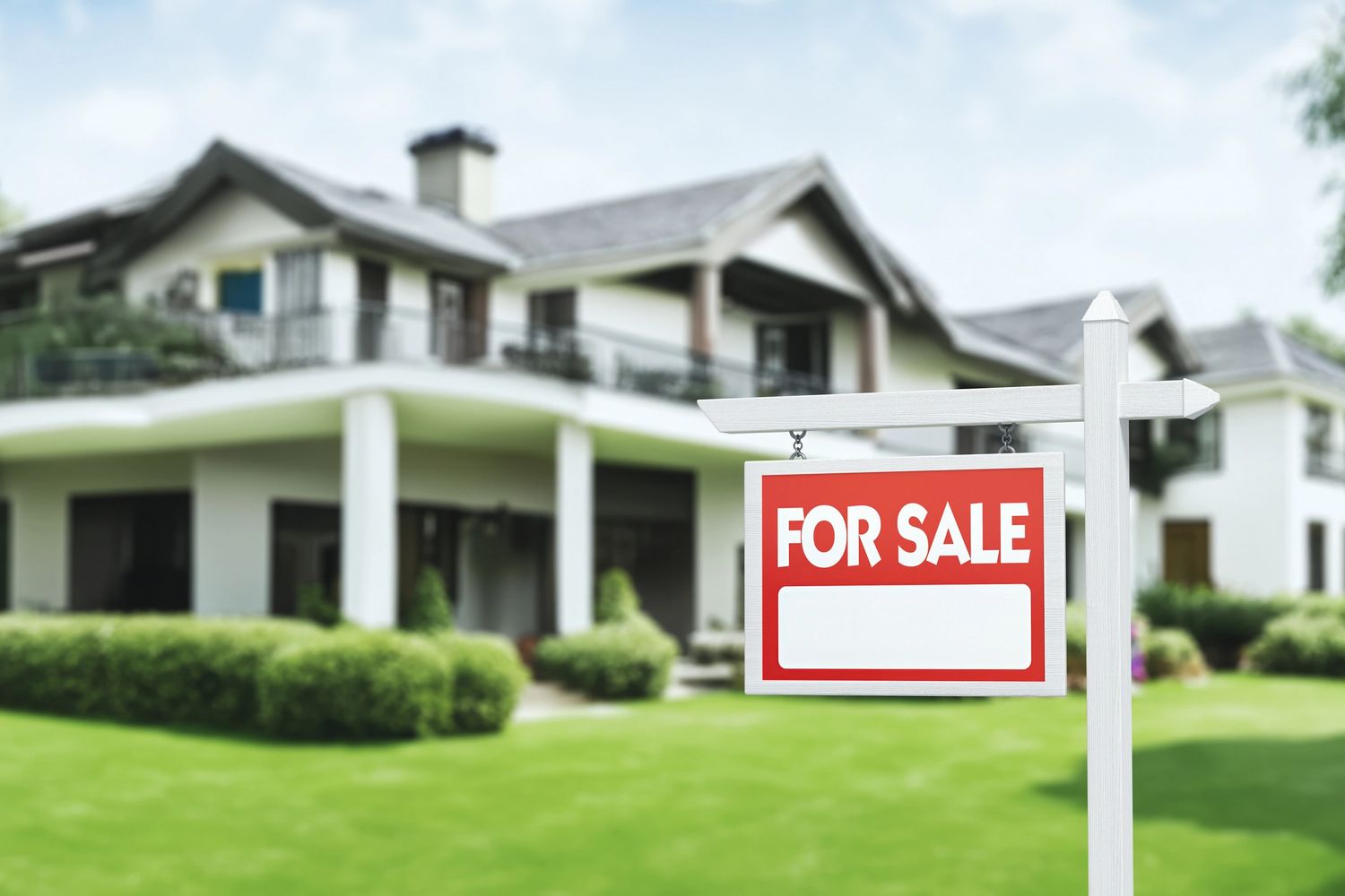 Modern house with a red and white for sale sign on the lawn.