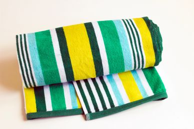 Striped green, yellow, and white beach towel rolled up.