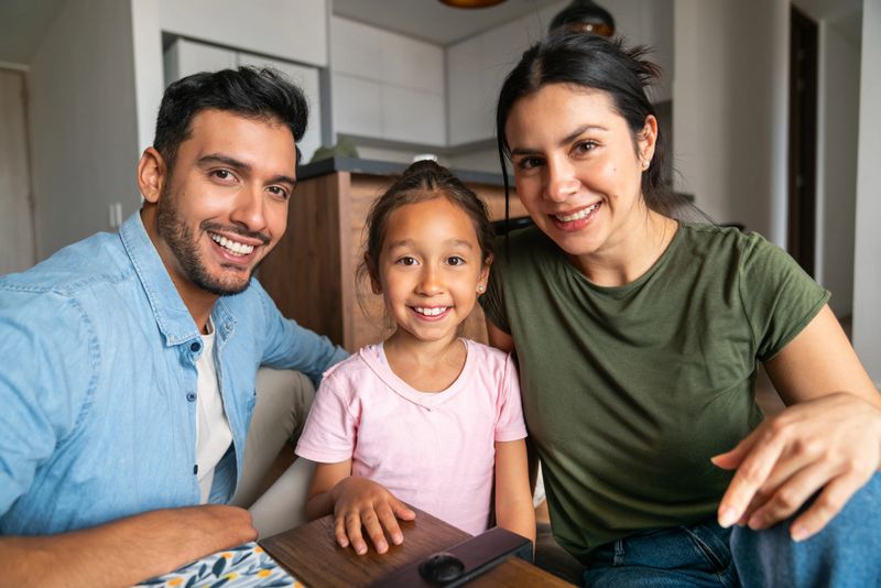 Portrait of a happy Latin American family relaxing at home and looking at the camera smiling