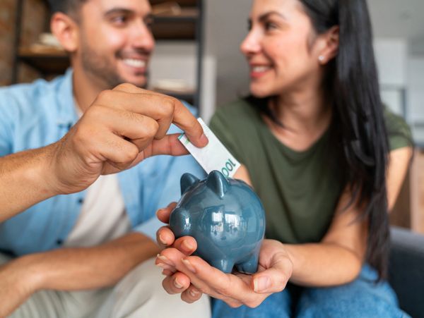 Couple saving money together with a piggy bank and a 100 bill.
