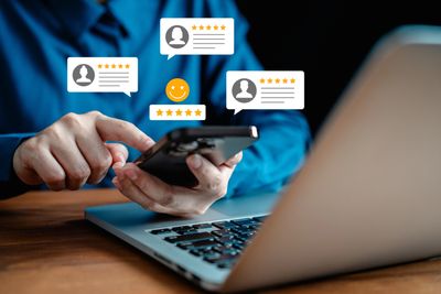 Person using smartphone with five-star review icons floating around.
