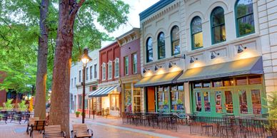 Charming tree-lined street with outdoor seating and historic storefronts at dusk.