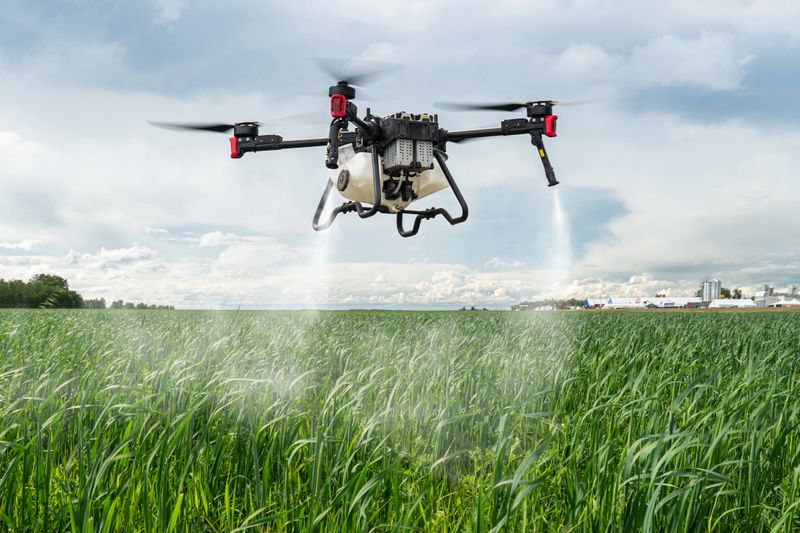 Agriculture drone against the background of blue sky and green fields with agricultural plants. drone for pollination of plants. Modern technologies in agriculture.
