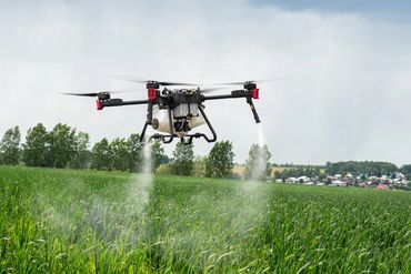 Drone spraying crops in a green agricultural field.
