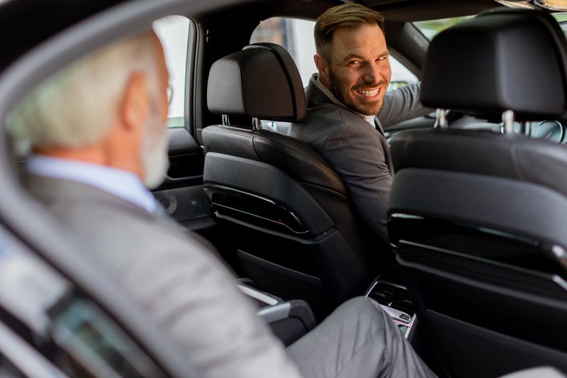 Cheerful man sits in the rear seat of a vehicle, sharing a moment of camaraderie with the driver