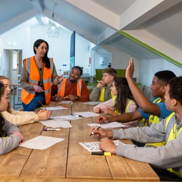 A safety briefing with construction workers wearing reflective vests around a table.