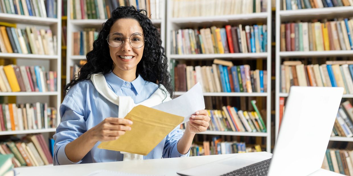 Woman standing behind the library and hold the paper With looking on the camera