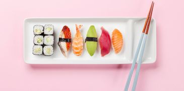 Colorful sushi assortment neatly arranged with chopsticks on a white plate.