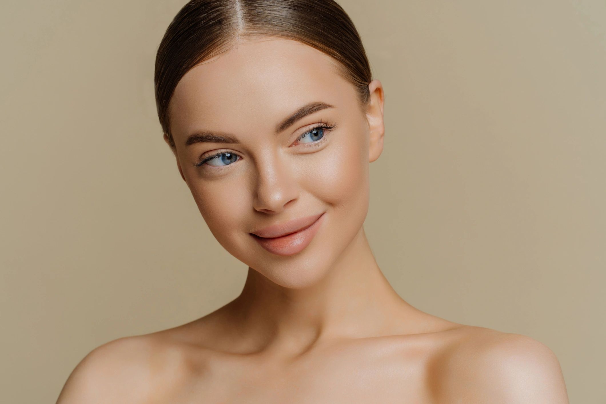Woman with clear, refreshed skin on a warm beige background