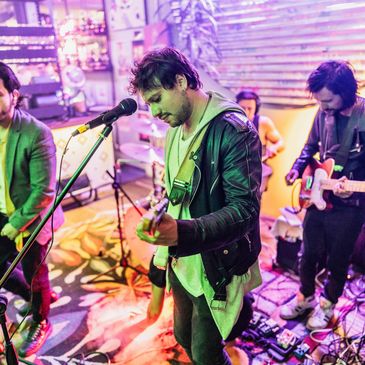 Band performing live in a vibrant, colorful indoor setting.