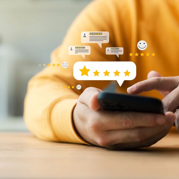 Person holding smartphone with digital star ratings floating above.