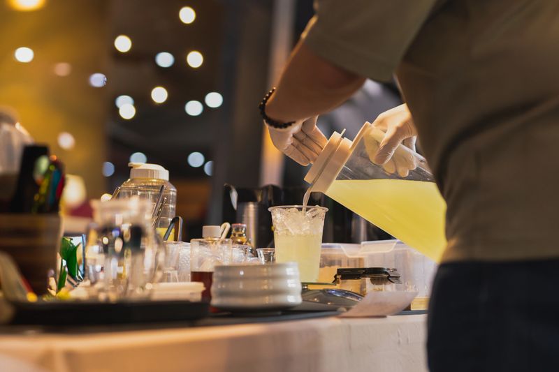 Man pouring juice from jar into a tak away glasses at the shop
