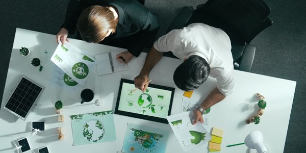 Two people reviewing eco-friendly and recycling charts at a white table.