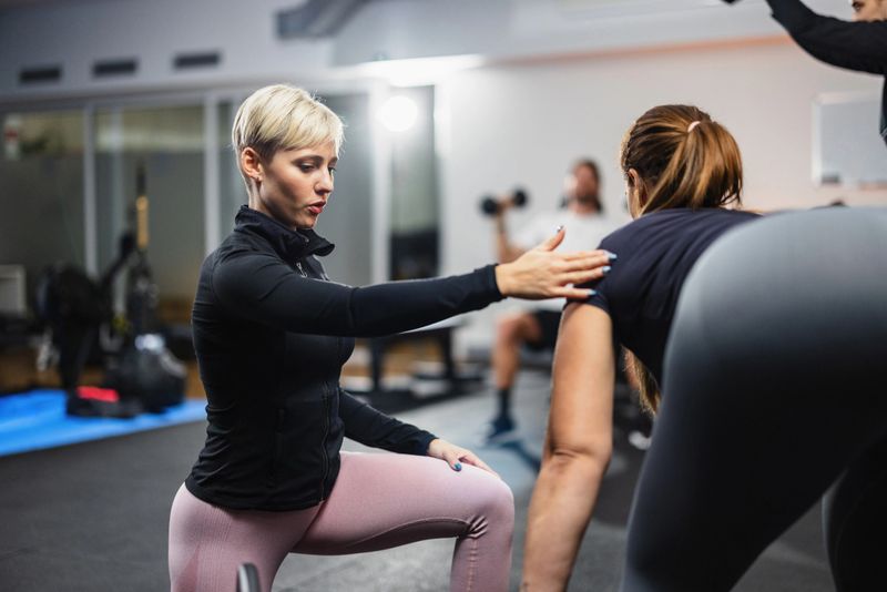 Focused personal trainer instructing a female client on proper exercise form, ensuring safe and effective training.