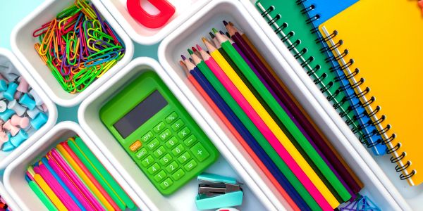 Colorful school supplies neatly arranged in trays.