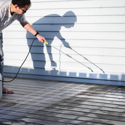 Person pressure washing a wooden deck.